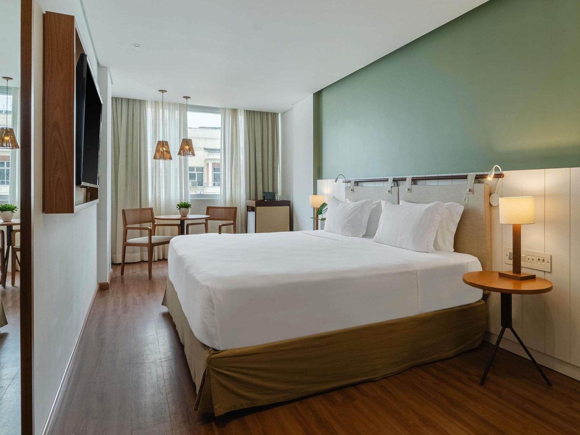 Quarto premium de luxo com cama king-size e vista parcial lateral do mar